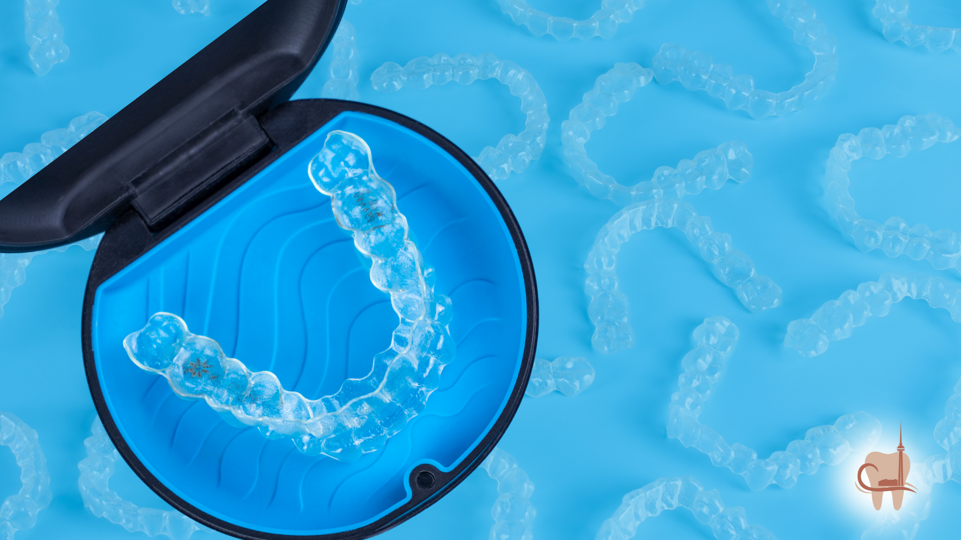 Clear aligners in a blue case, with additional aligners scattered on a blue surface.