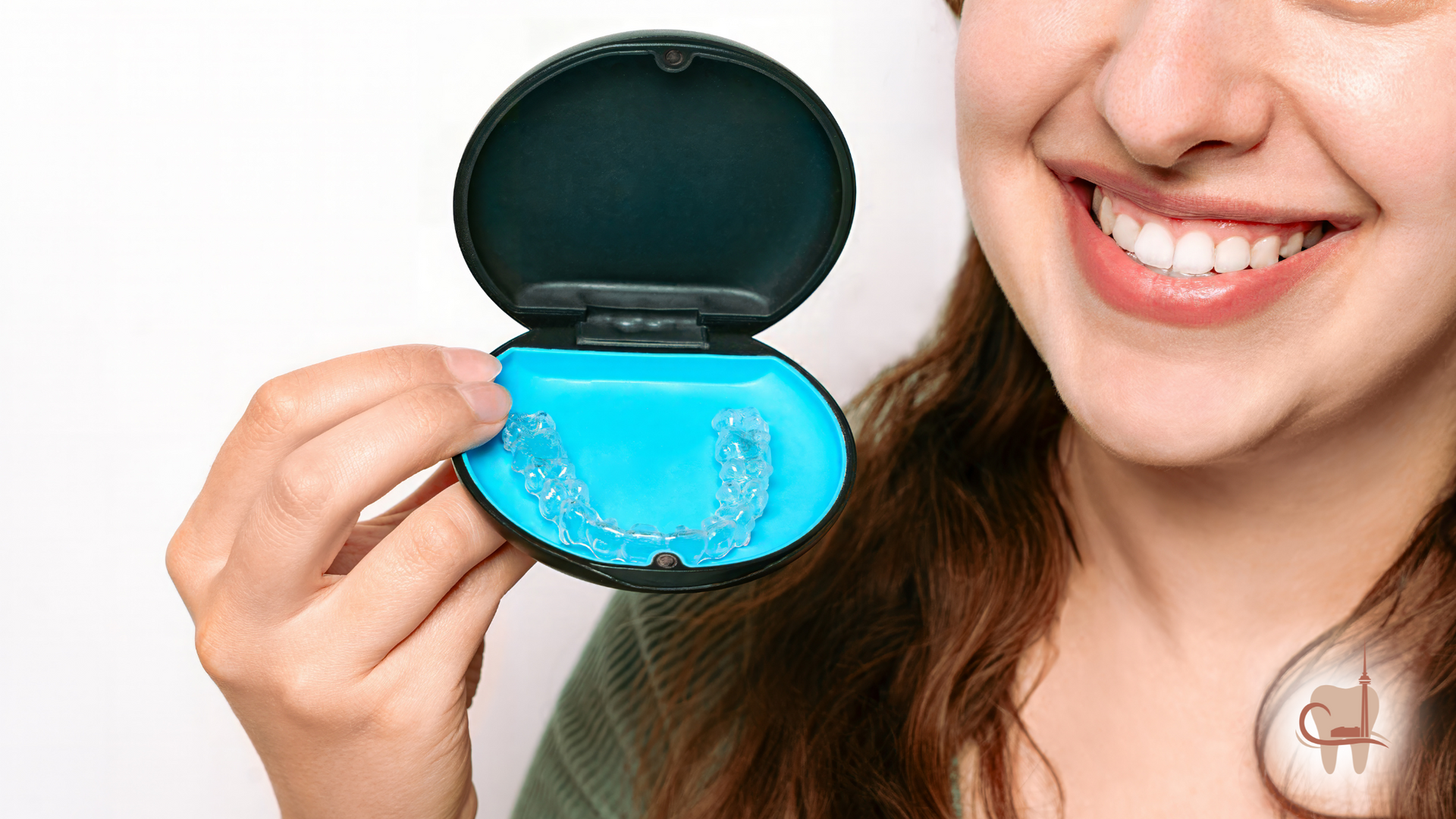 Woman smiling, holding open case with blue dental retainer.
