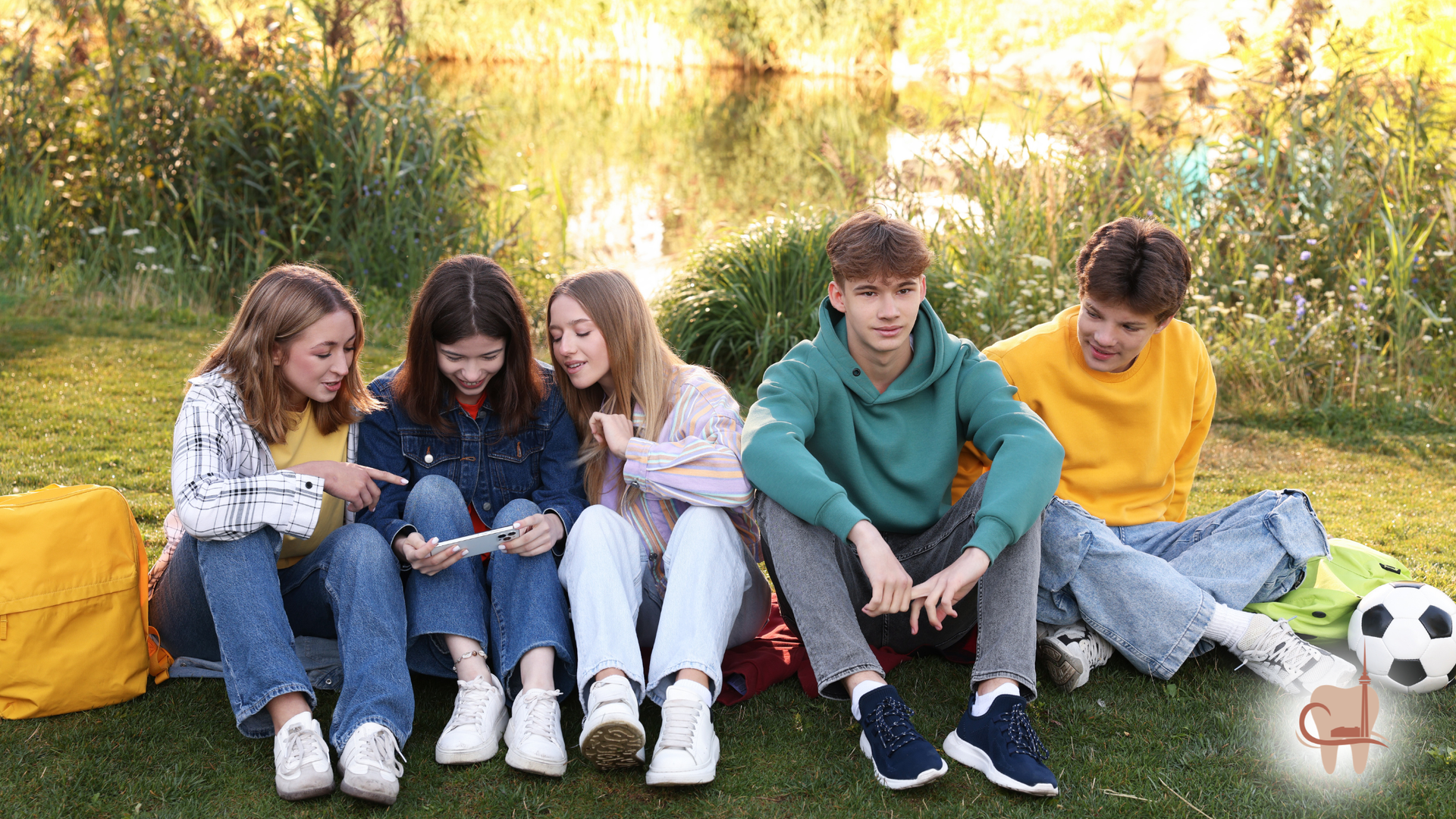 Four smiling people huddle together under a blue sky, arms around each other, looking down.