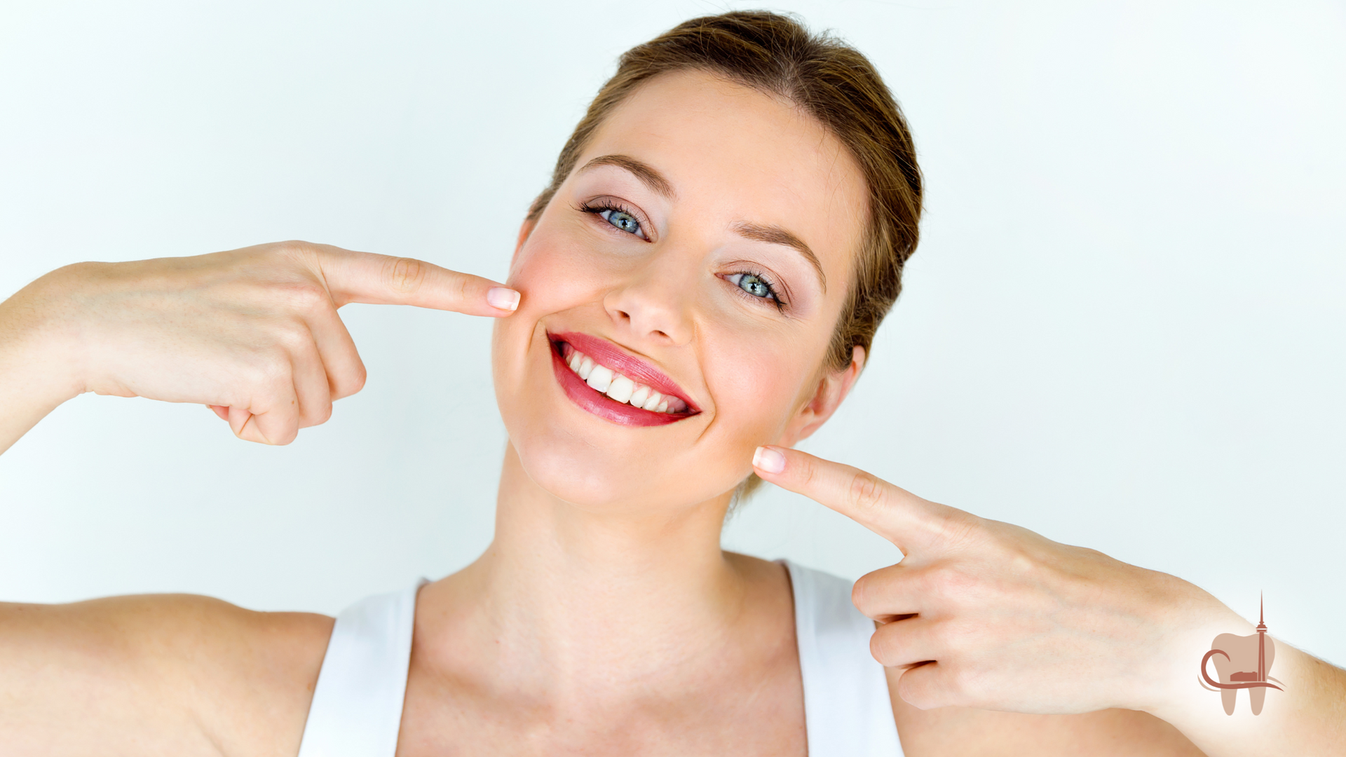 Woman with fair skin and blue eyes smiles, pointing to cheeks.