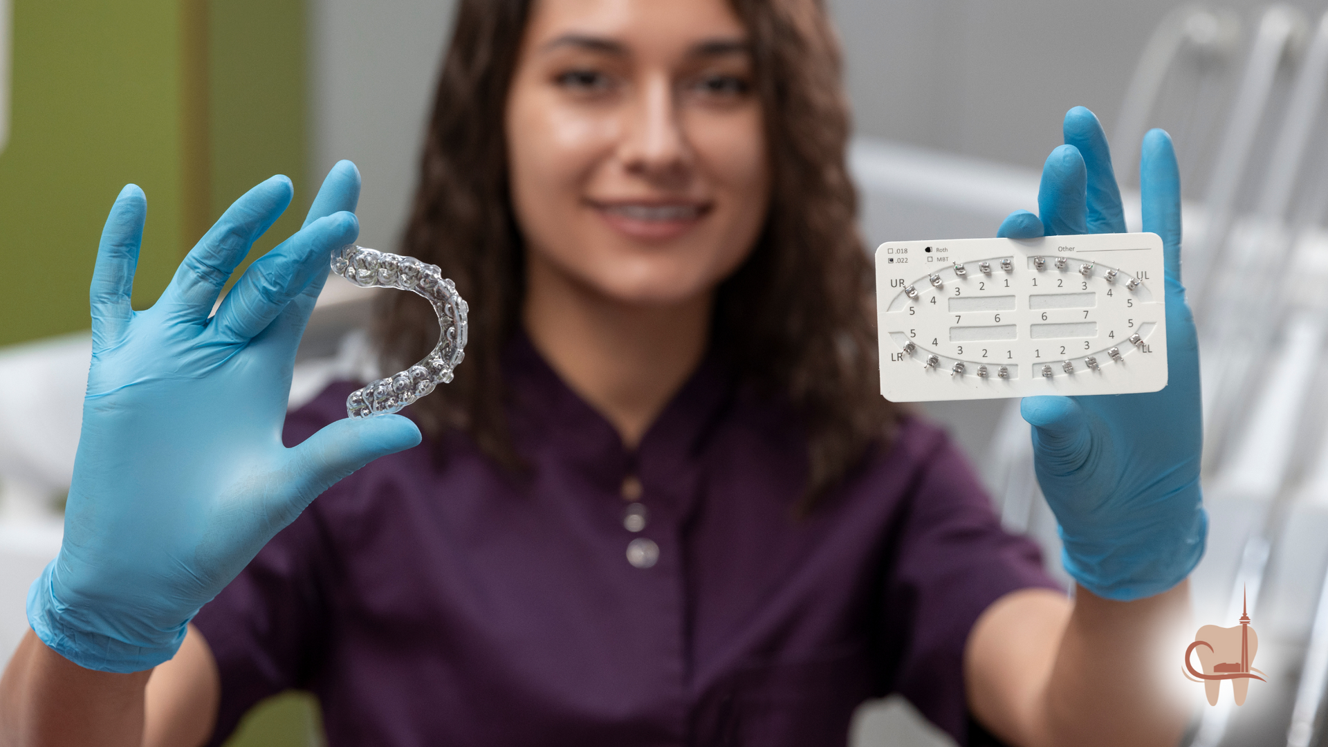 Woman in blue gloves holding clear aligner and tooth chart in dental office.