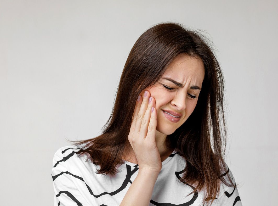 A woman is holding her face in pain because of a toothache.