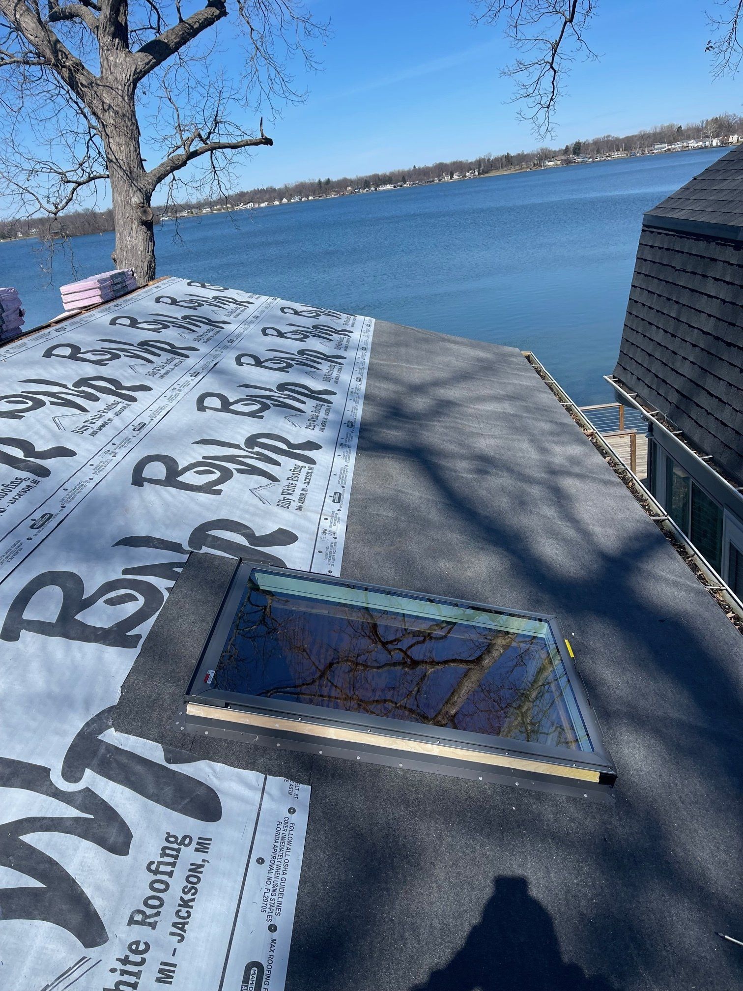 Roof under construction with skylight, lake background, blue sky.