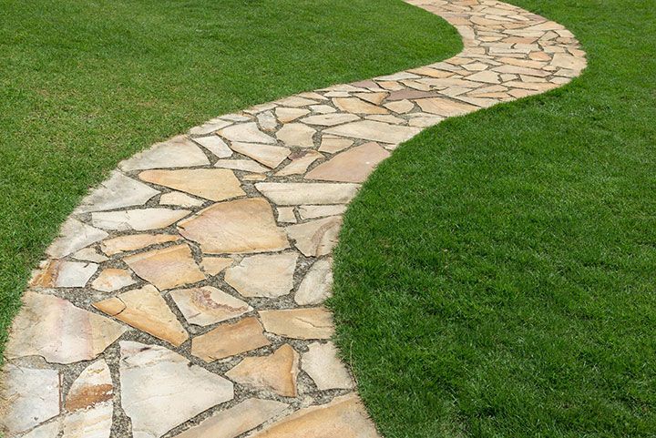 Stone path on green grass in the garden 
