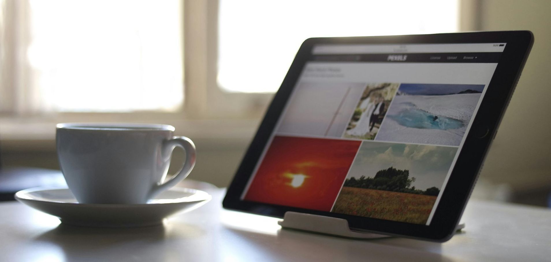 A tablet is sitting on a table next to a cup of coffee.