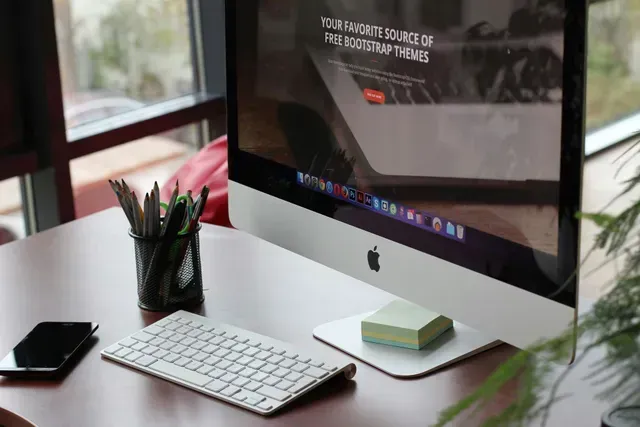 An apple computer is sitting on top of a wooden desk.