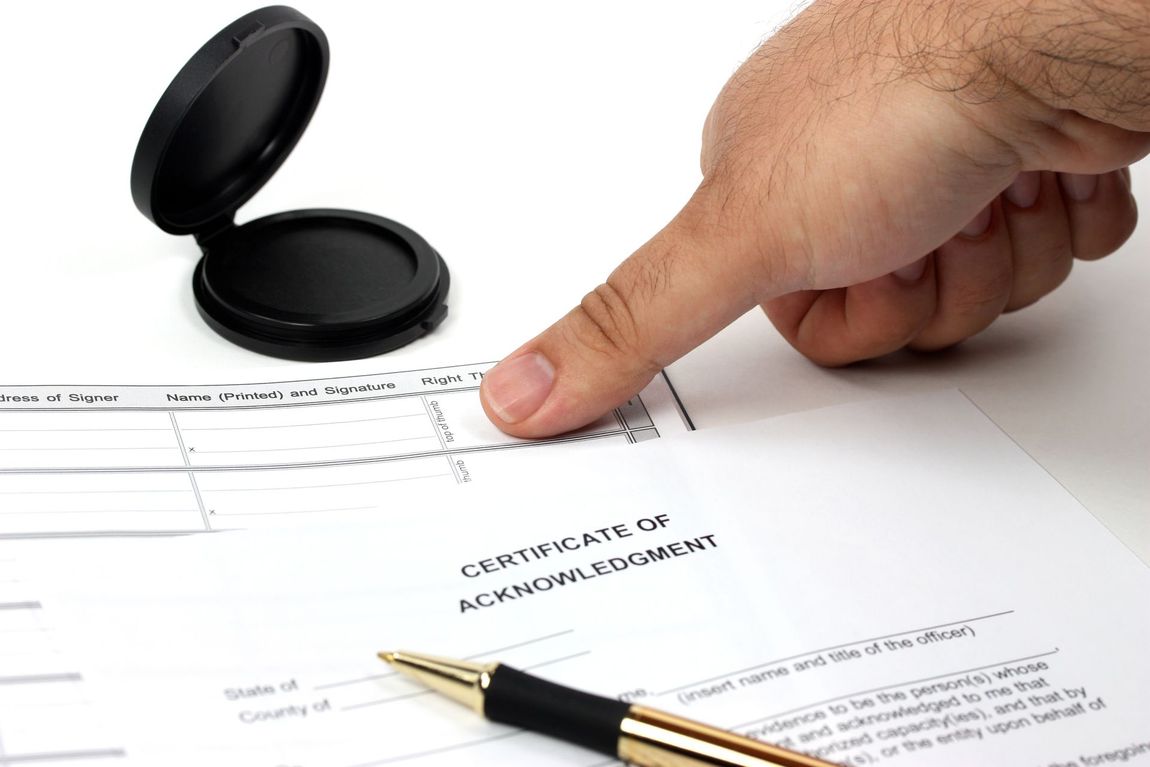 Hand stamping a certificate of completion beside a pen and open stamp case