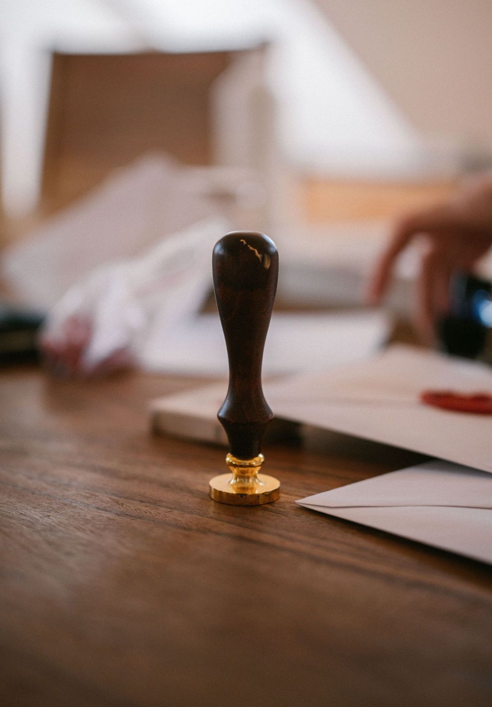 Black wax seal stamp standing on papers on a wooden table, with an open envelope in the background