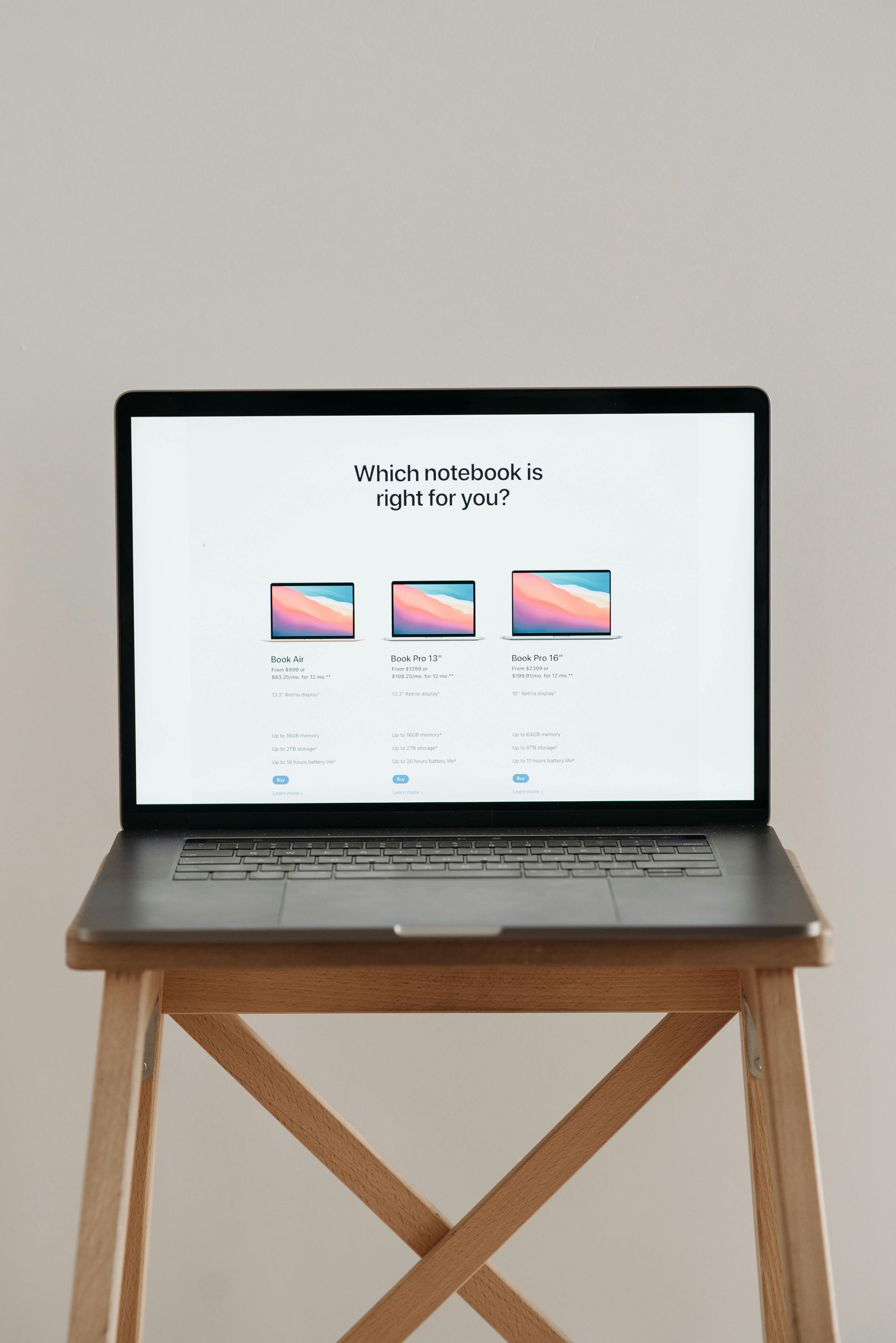 Bärbar dator som visar en jämförelse av tre bärbara datorstorlekar, placerad på en träpall mot en vit vägg.