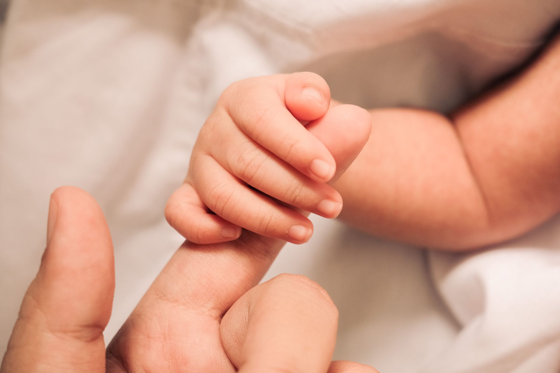 A close up of a person holding a baby 's hand.