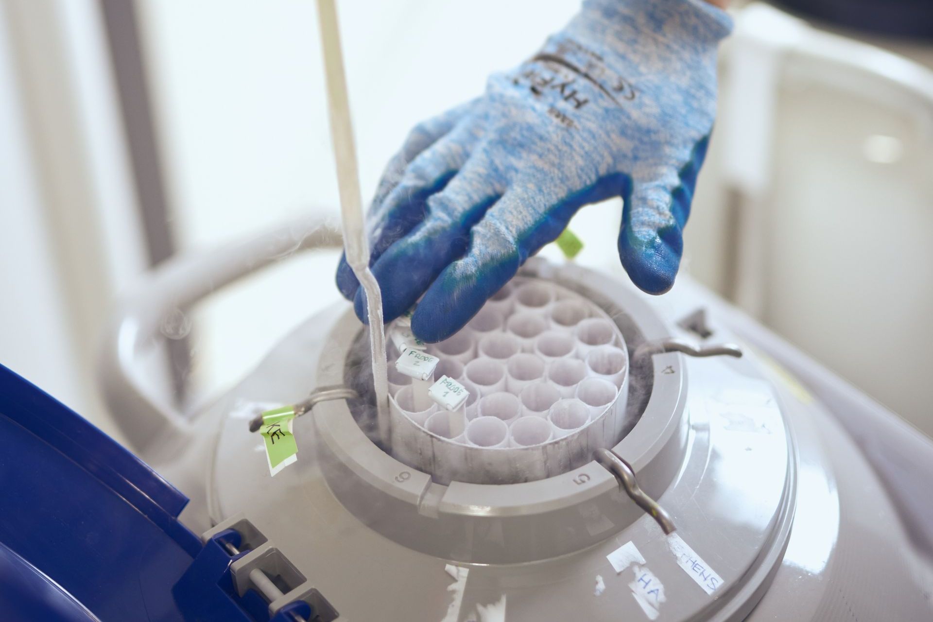 A person wearing blue gloves is working on a machine.