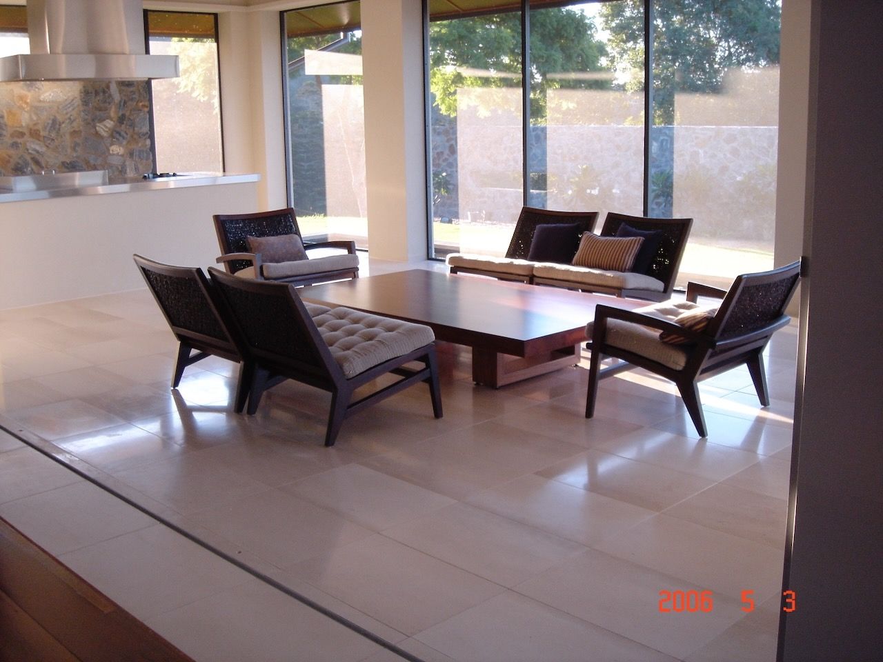 Living room with modern dark wood furniture, large windows, and beige floor.