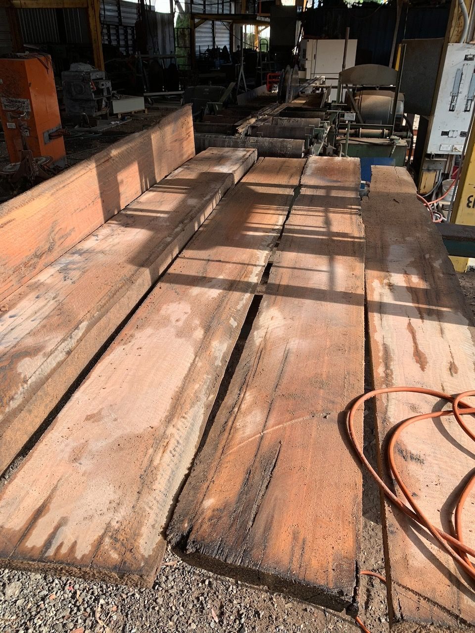 Wooden planks laid out on a concrete surface, possibly at a lumber mill.