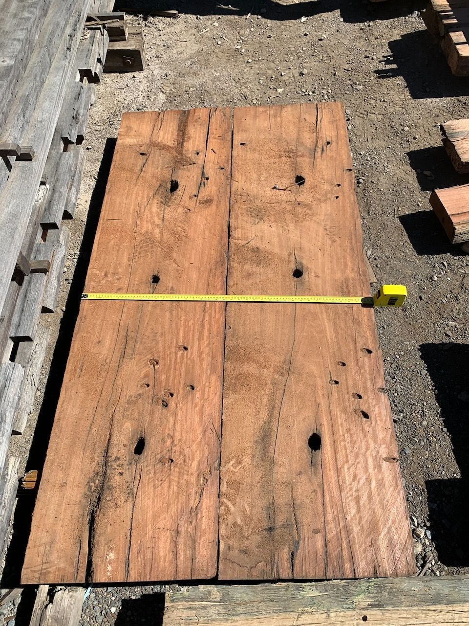 Four rectangular wooden planks lying flat, with a measuring tape across them.