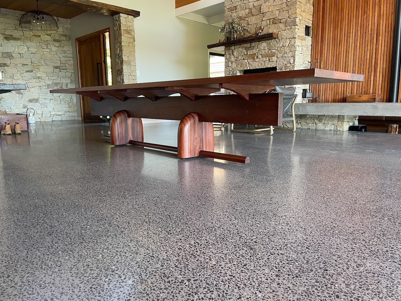 Long wooden table on polished concrete floor, with stone and wood walls.