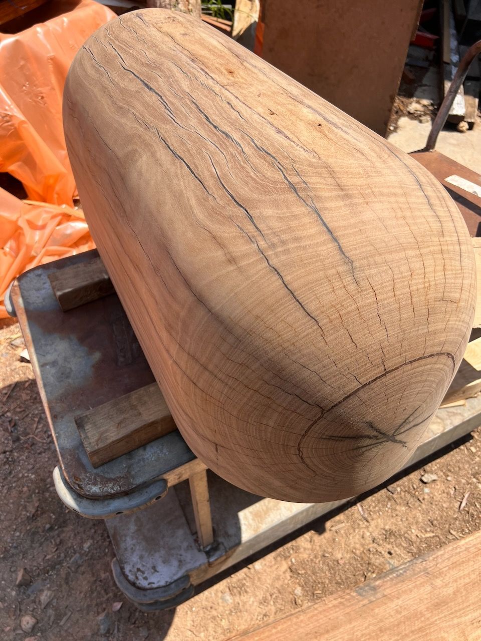 Large, rounded wooden form on a work surface, showing visible wood grain and cracks.