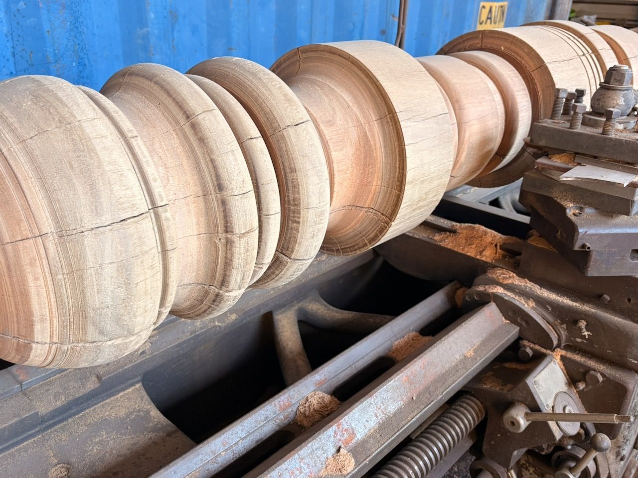 Wood being turned on a lathe, forming a decorative column.