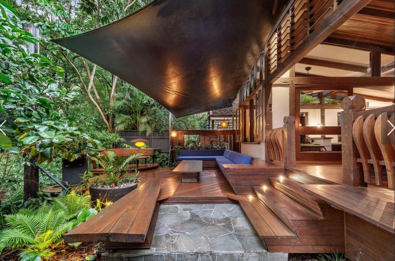 Wooden deck with shade sail, leading to an open-air seating area with greenery in Brisbane.