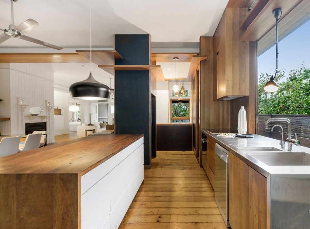 Wooden kitchen with stainless steel appliances, and a view to the outside.