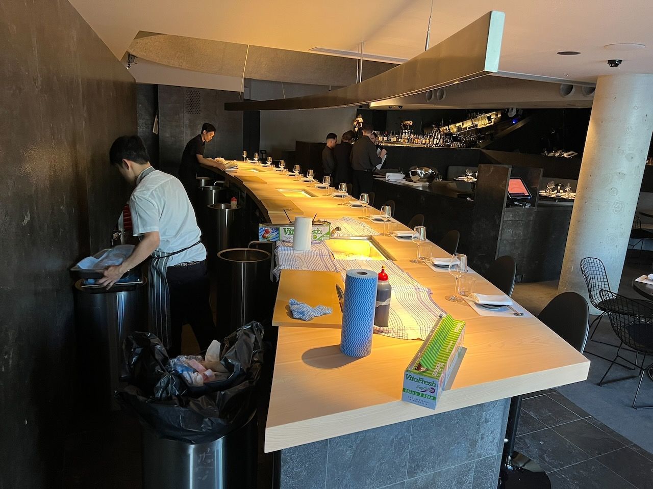 Sushi bar interior; staff cleaning and preparing the counter.
