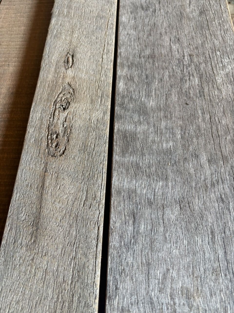 Two weathered gray wooden planks side-by-side, showing wood grain and a knot in Brisbane.