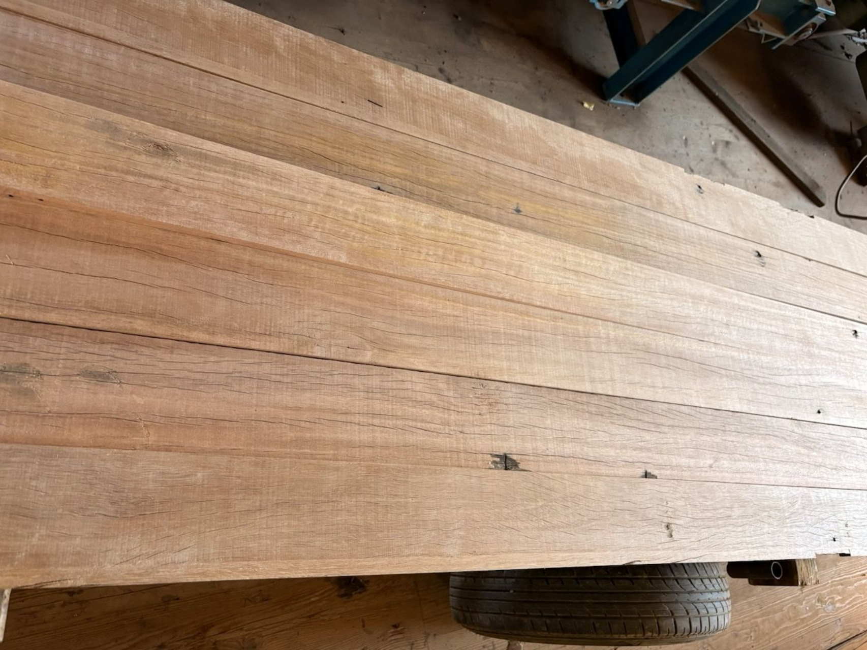 A high-angle view of multiple parallel wooden planks laid side-by-side to form a flatbed surface above a trailer tire.