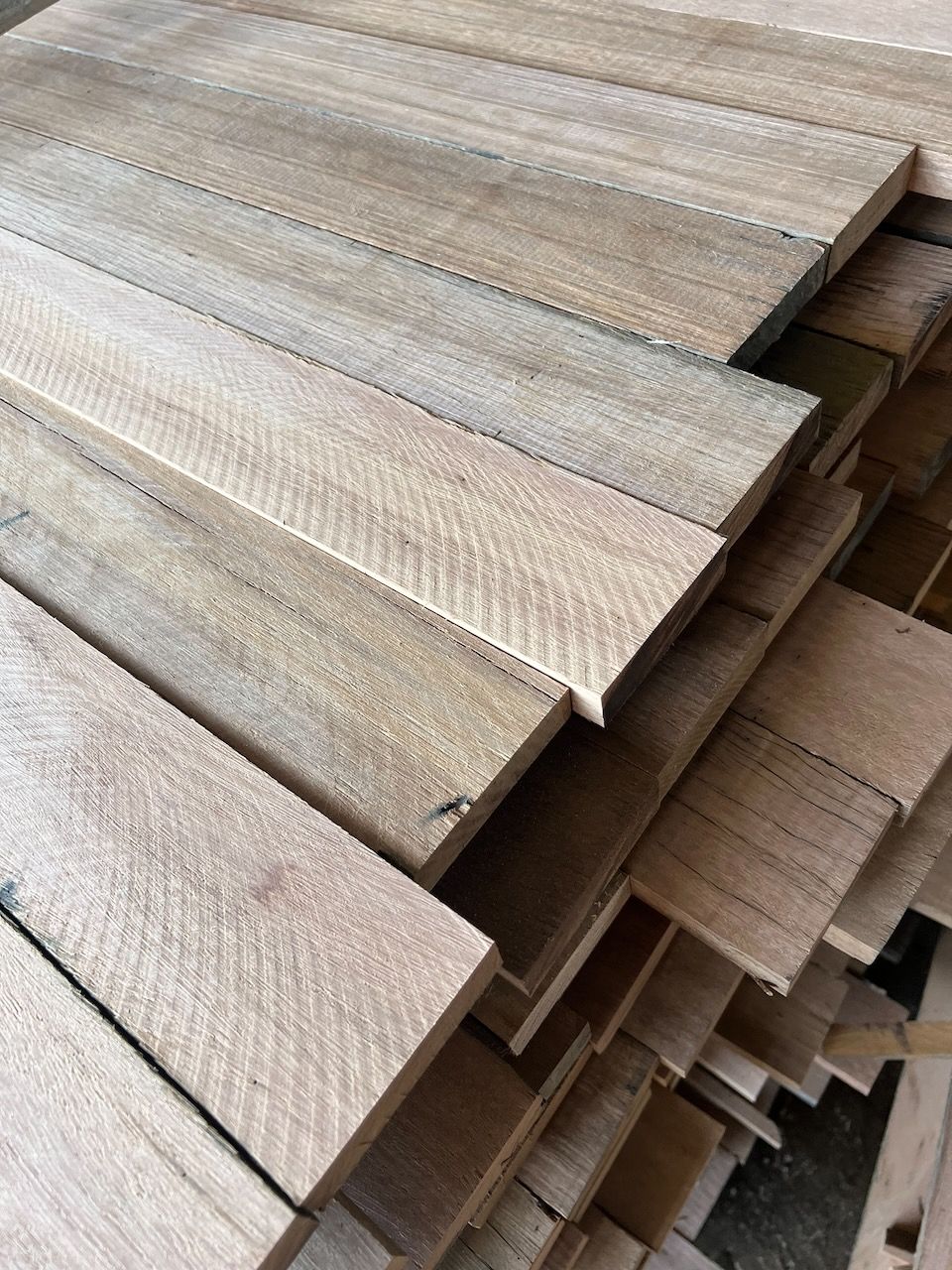 Stack of weathered wooden planks with visible grain, varying in color from light to medium brown.