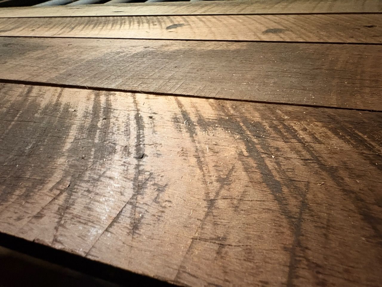 Close-up of weathered wooden planks with a dark, textured grain and linear surface scratches.