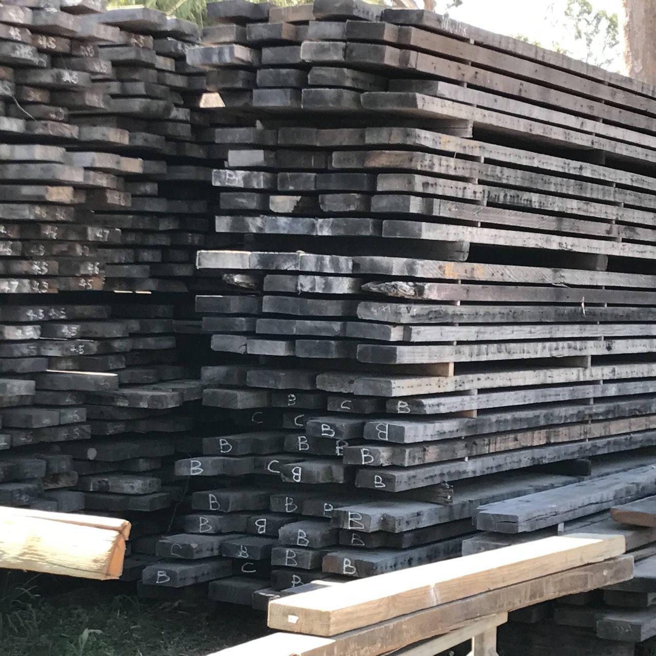 Stacks of weathered lumber, gray and brown hues, outdoors.