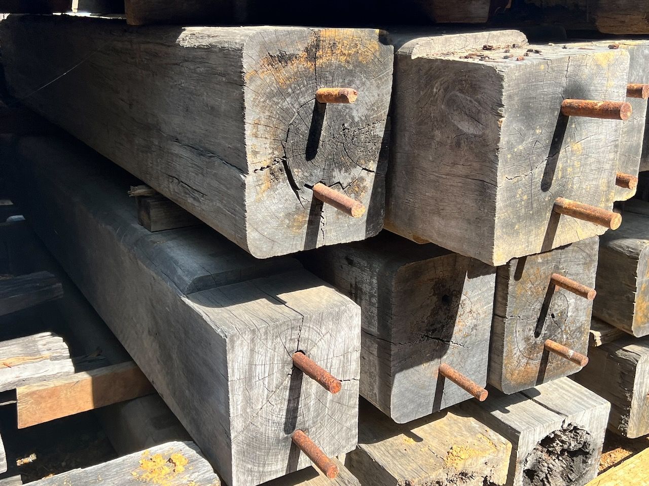 Stack of weathered wooden railroad ties with rusty metal spikes.