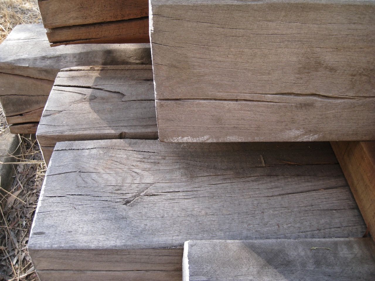 A close-up view of stacked, weathered timber railroad ties with visible wood grain and surface cracks.