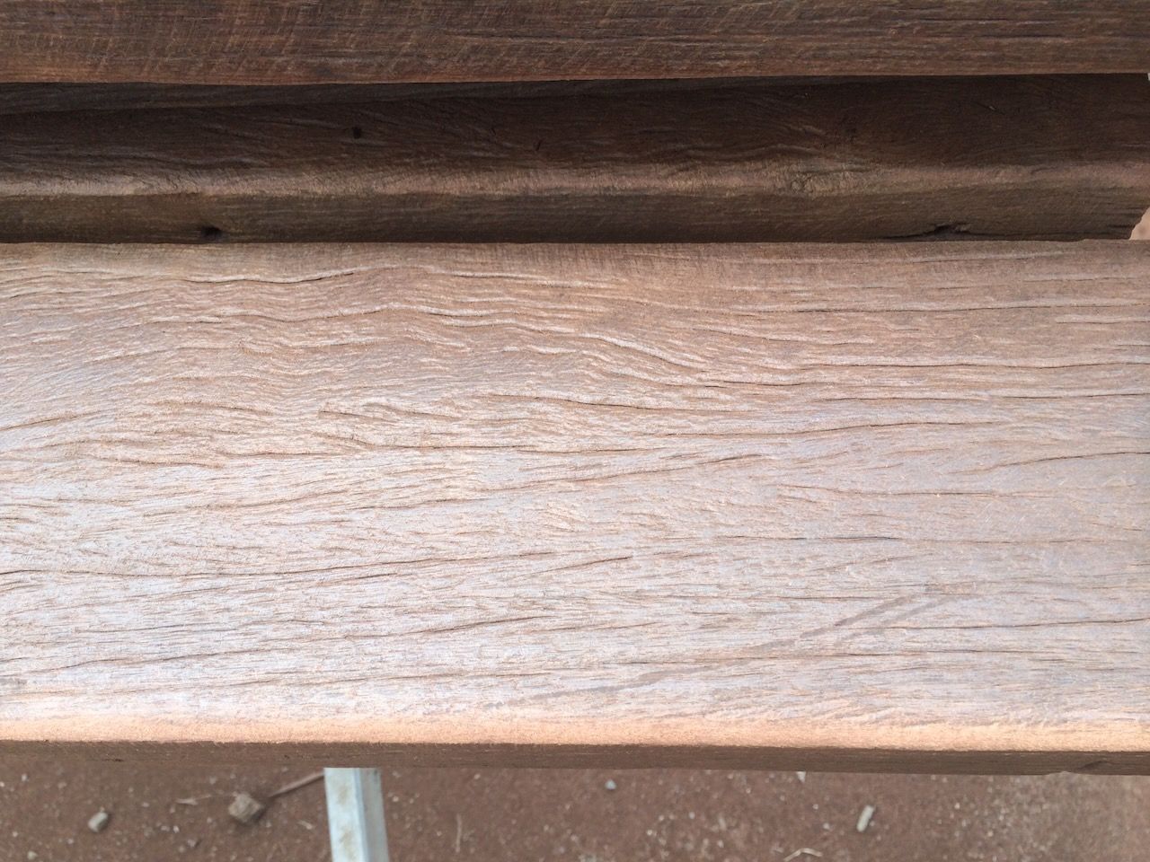 Close-up of weathered, light brown wood planks stacked horizontally.