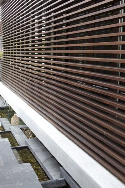 Wooden slat screen over a water feature with stepping stones and a modern, silver-colored base in Brisbane.