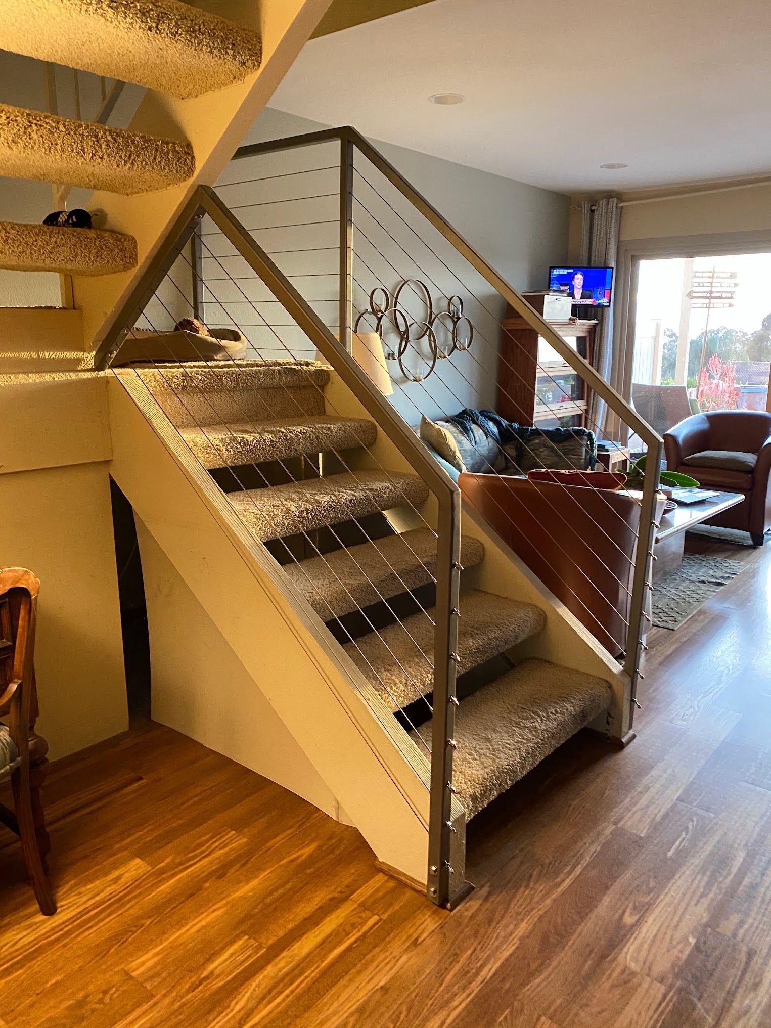 A staircase in a living room with a stainless steel railing.