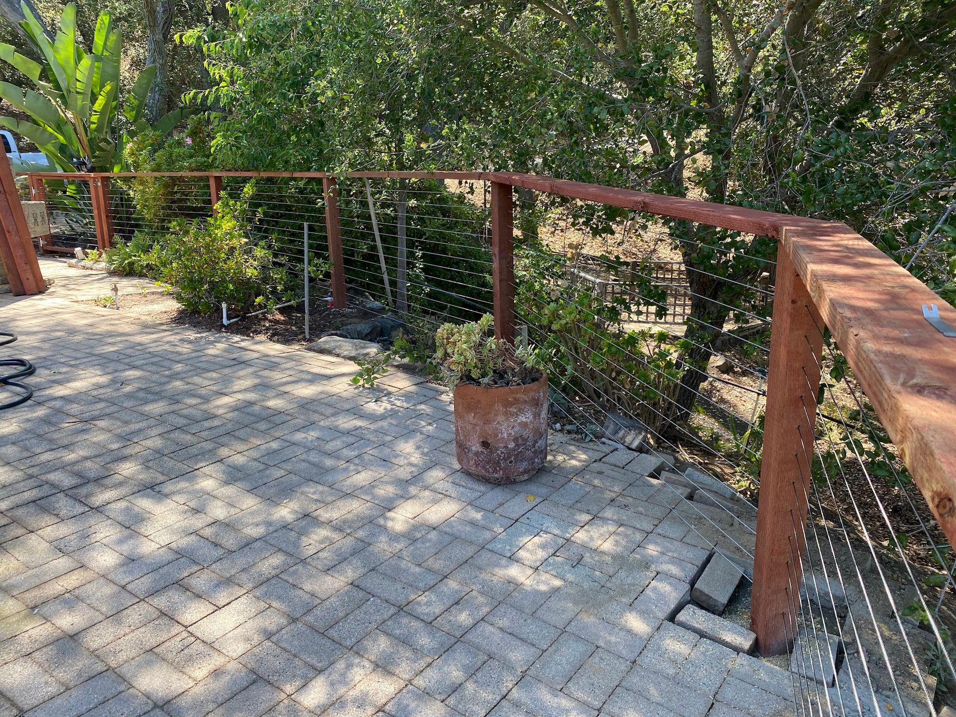 A patio with a wooden railing and a potted plant on it.