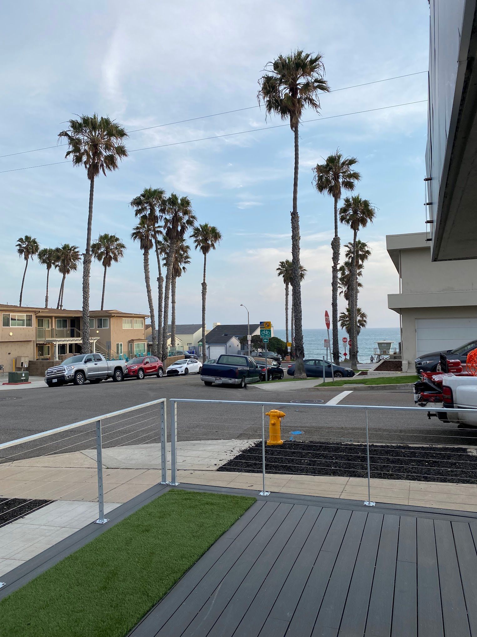 A row of palm trees are lined up on the side of the road