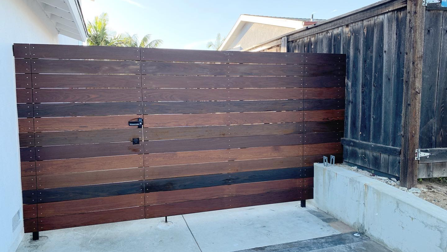 A wooden fence is sitting next to a black fence.