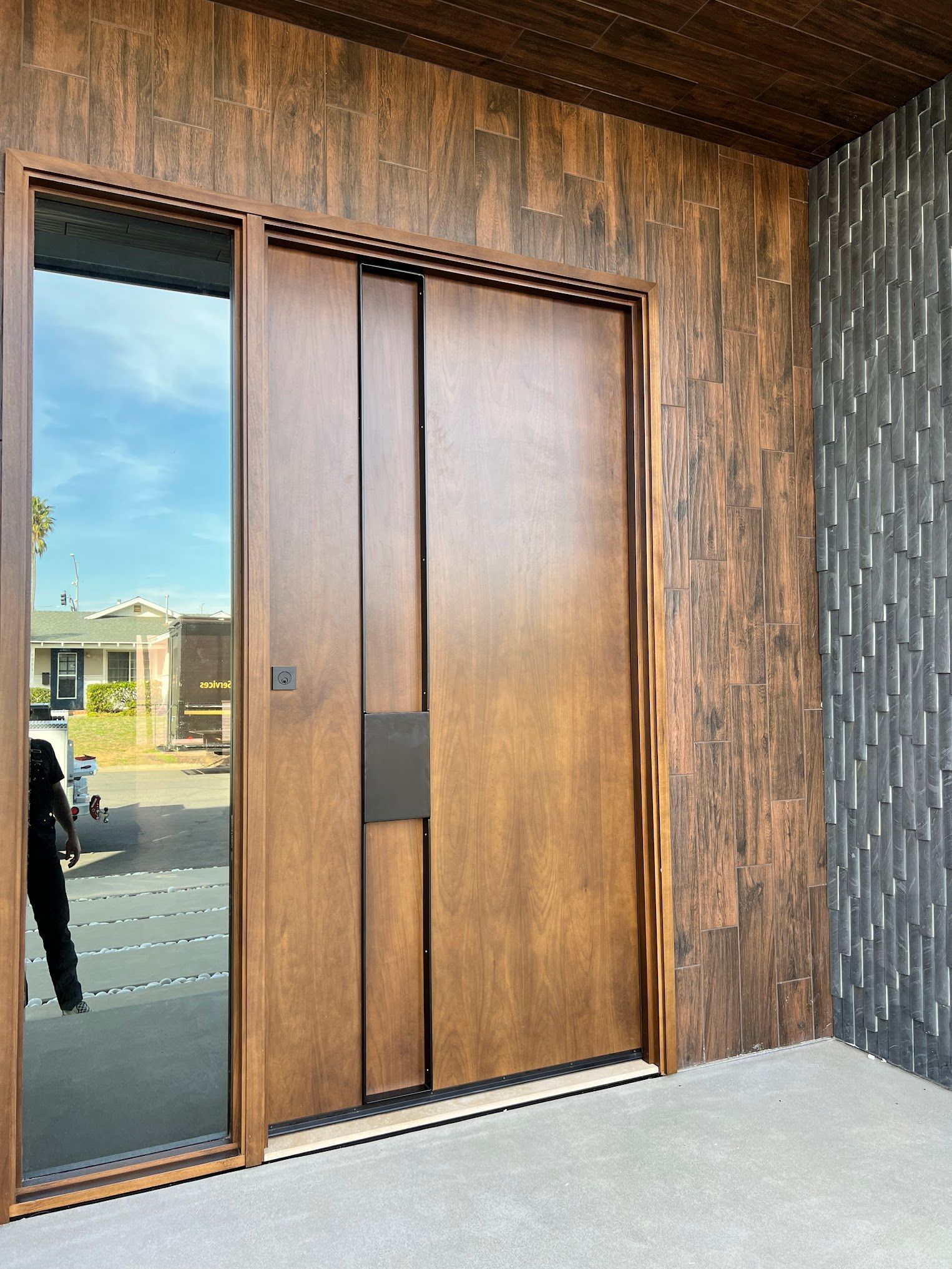 A large wooden door with a reflection of a car in it.