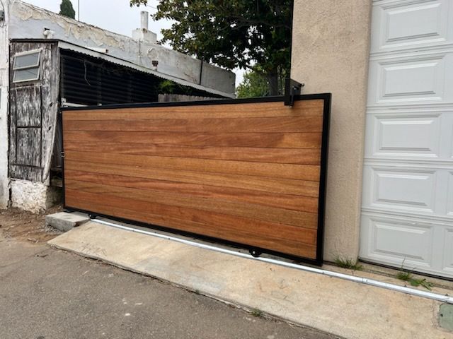 A wooden gate is sitting in front of a garage door.