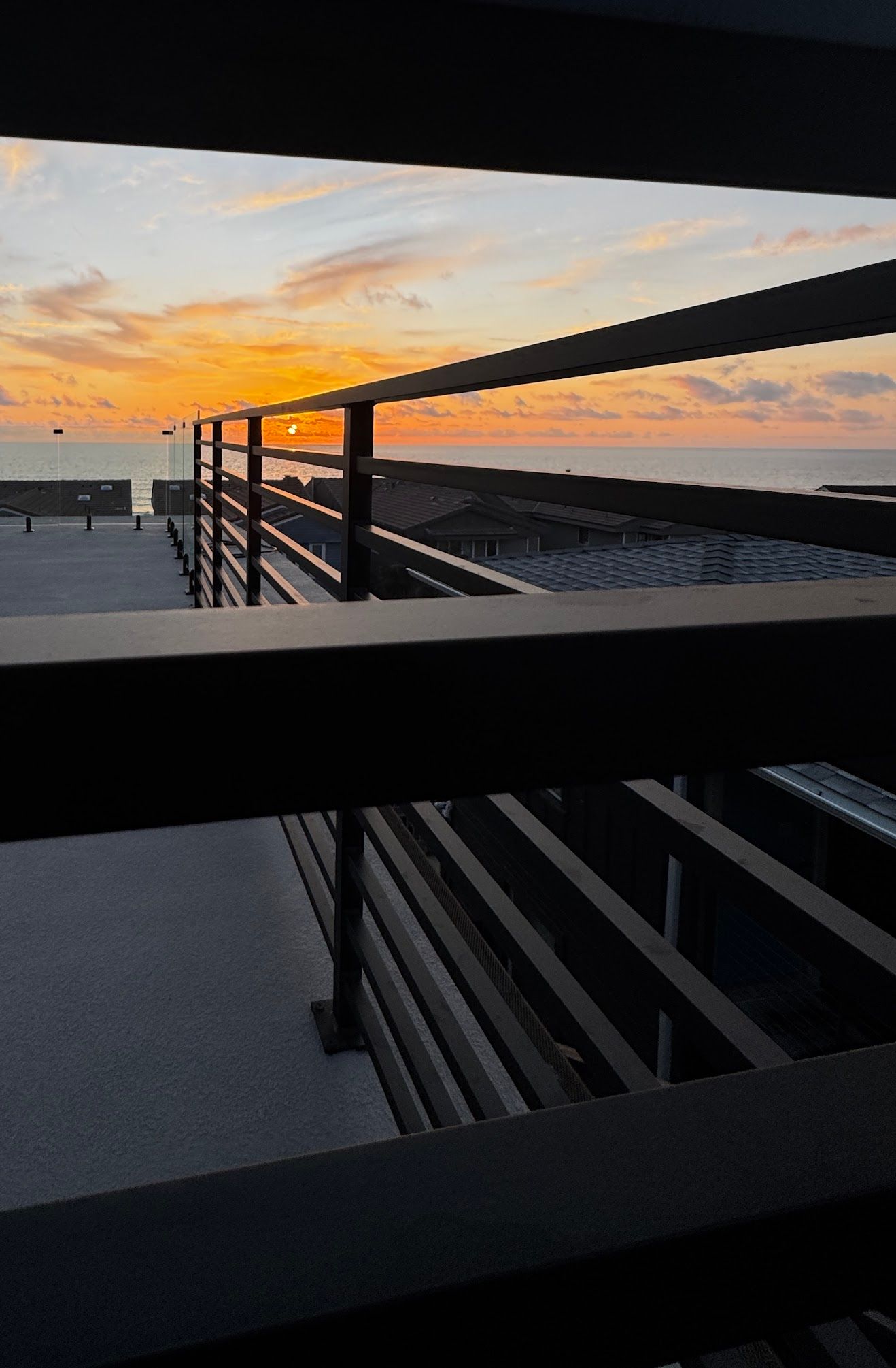 A view of the ocean from a balcony with a sunset in the background.