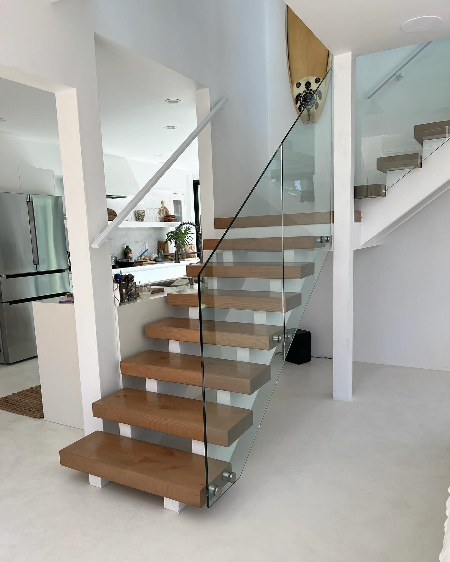 A wooden staircase with a glass railing in a house.