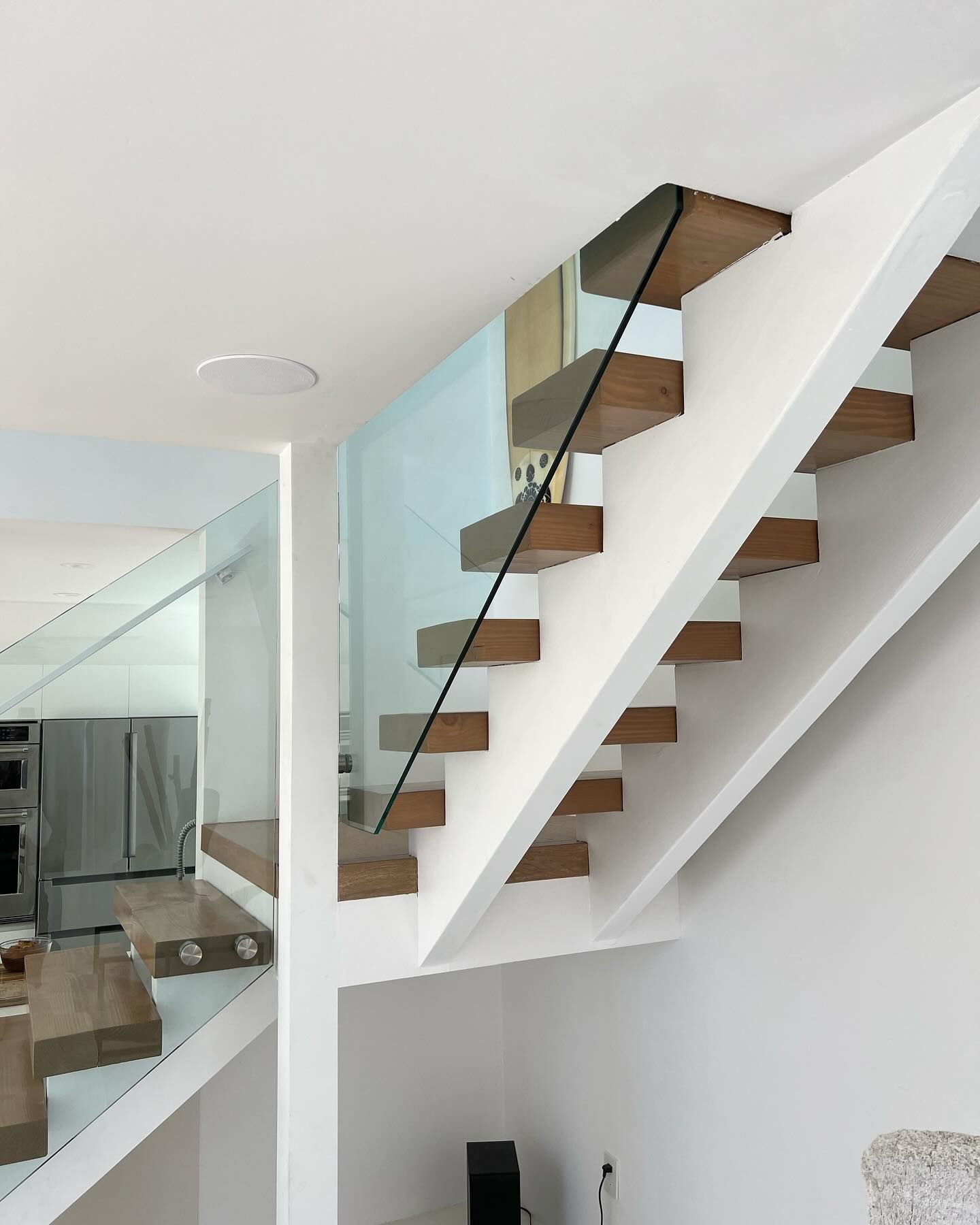 A white staircase with wooden steps and a glass railing