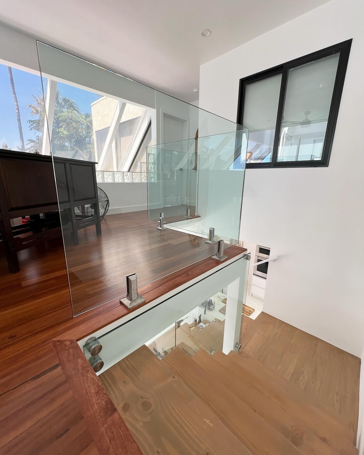 A staircase with a glass railing and a window in a house.