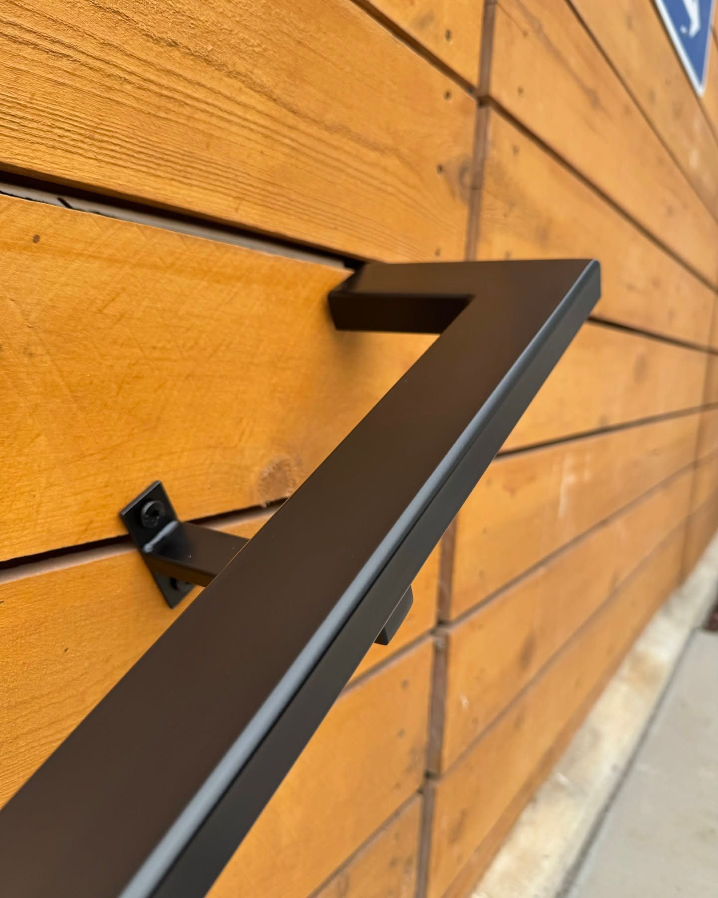 A black railing is attached to a wooden wall