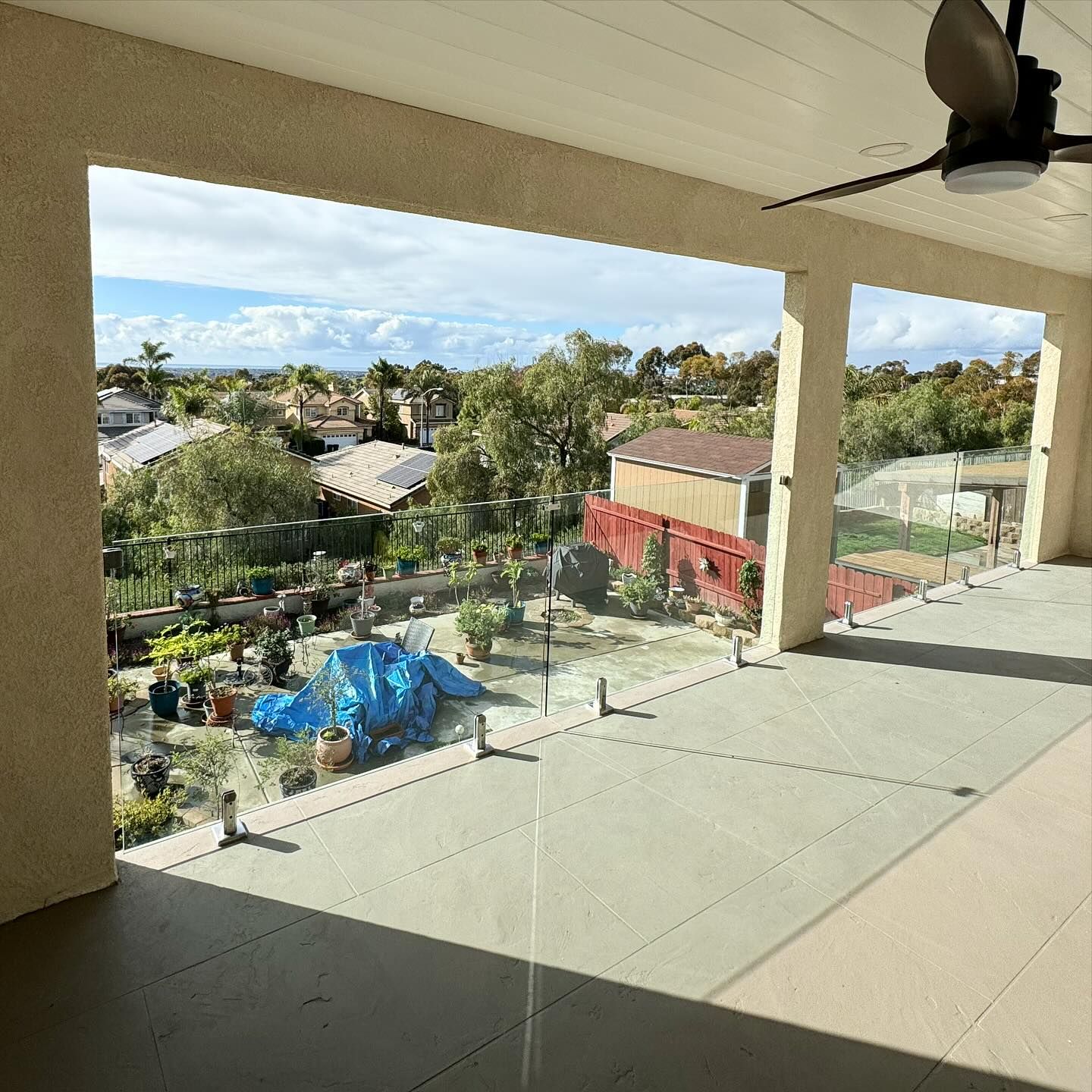 A balcony with a glass railing and a ceiling fan