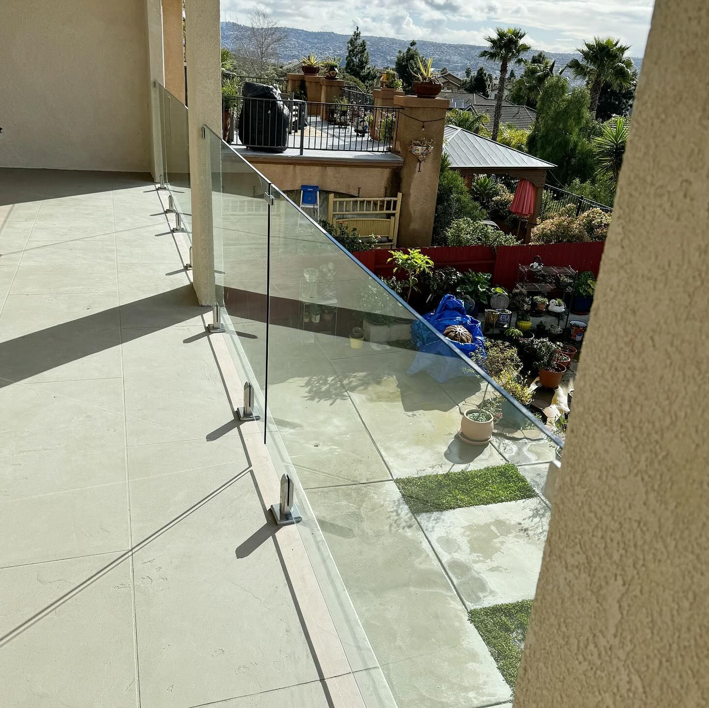 A balcony with a glass railing and a view of a house