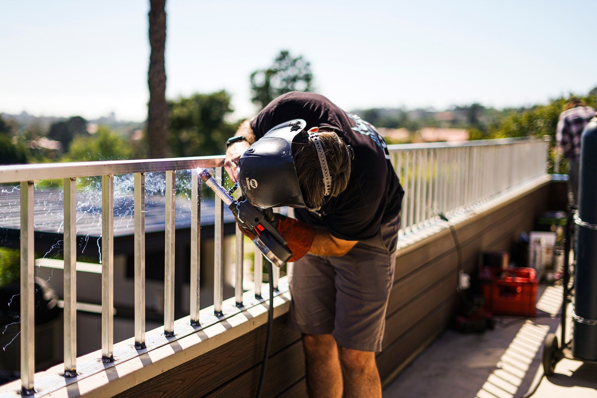 A man is welding a railing on a balcony.