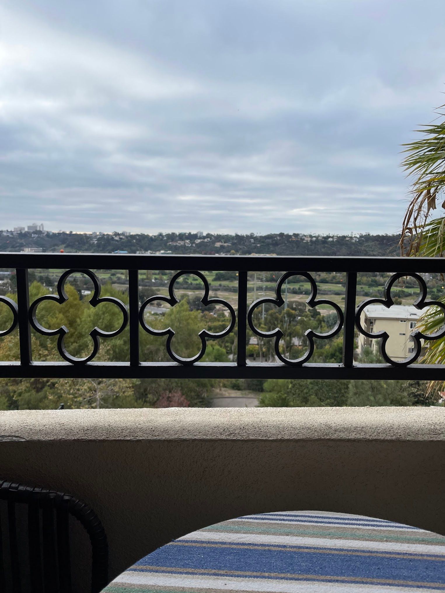 A balcony with a table and chairs and a wrought iron railing.