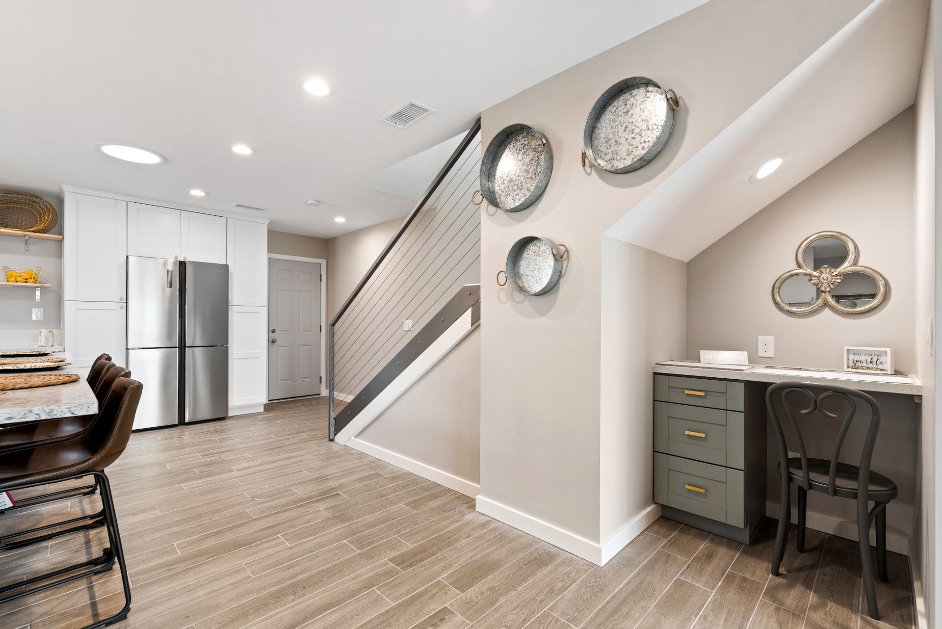 A living room with a staircase and a desk in the corner.