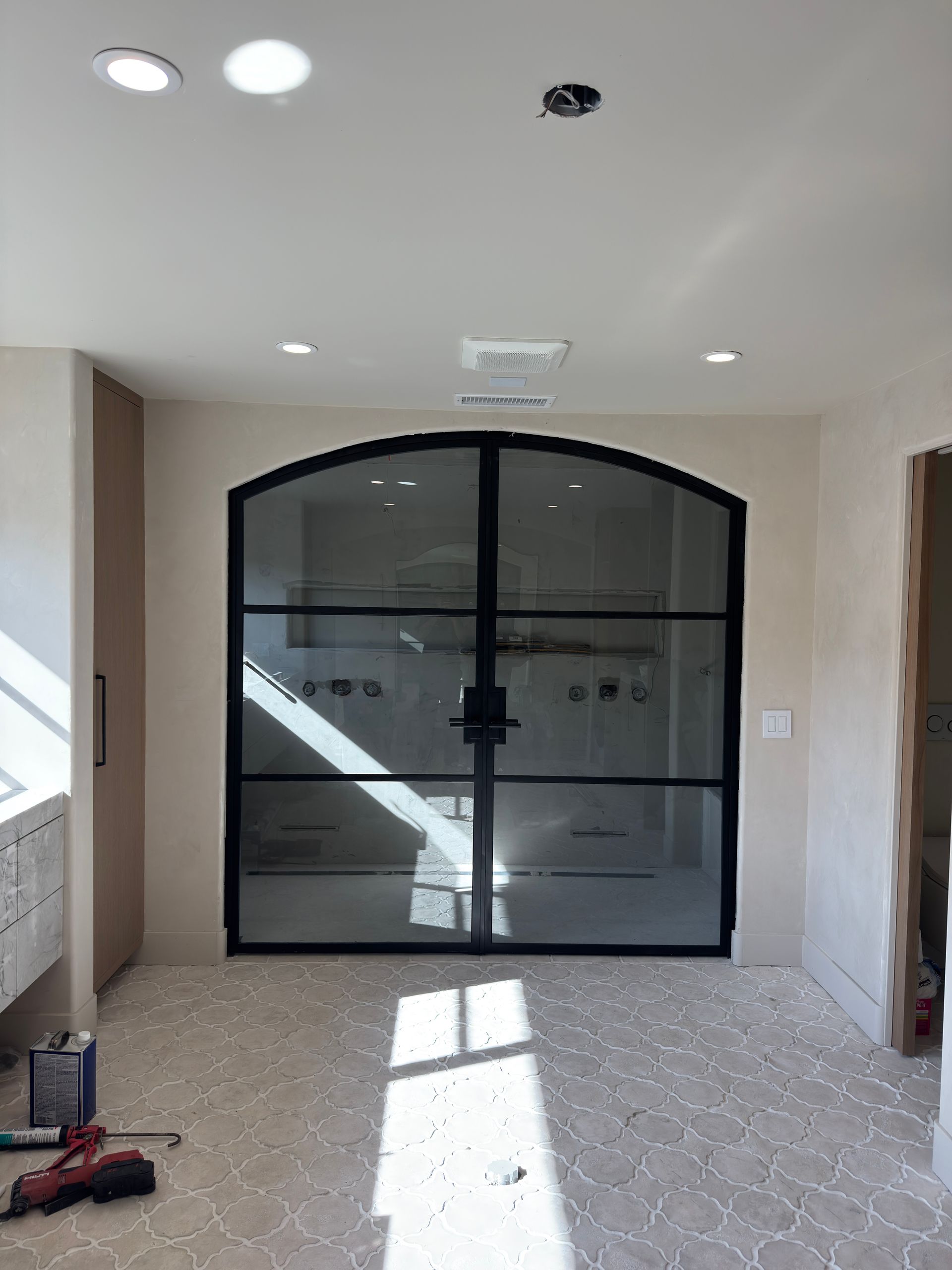 A room with a large glass door and a drill on the floor.